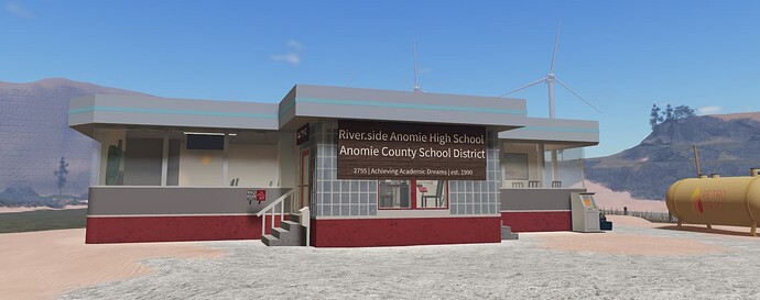 Riverside Anomie High School of the Anomie County School District stands as a red-and-gray building in a sandy landscape with wind turbines in the background. (Captioned by AI)
